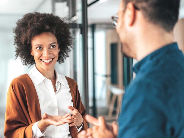 Un uomo e una donna conversano allegramente in ufficio